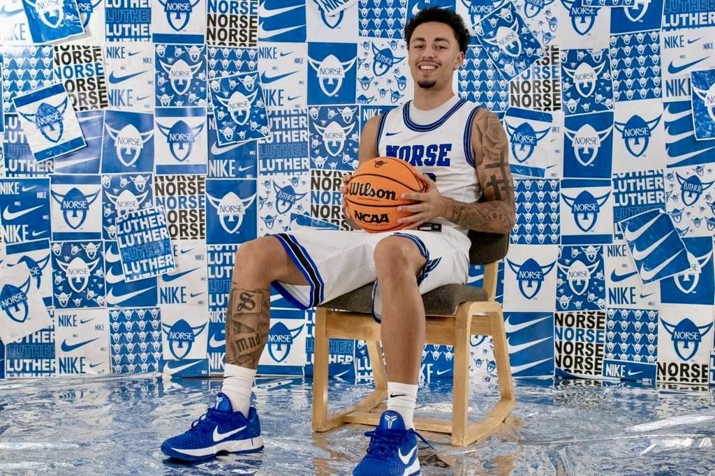 Kyanu seated with a ball in front of a Norse poster wall
